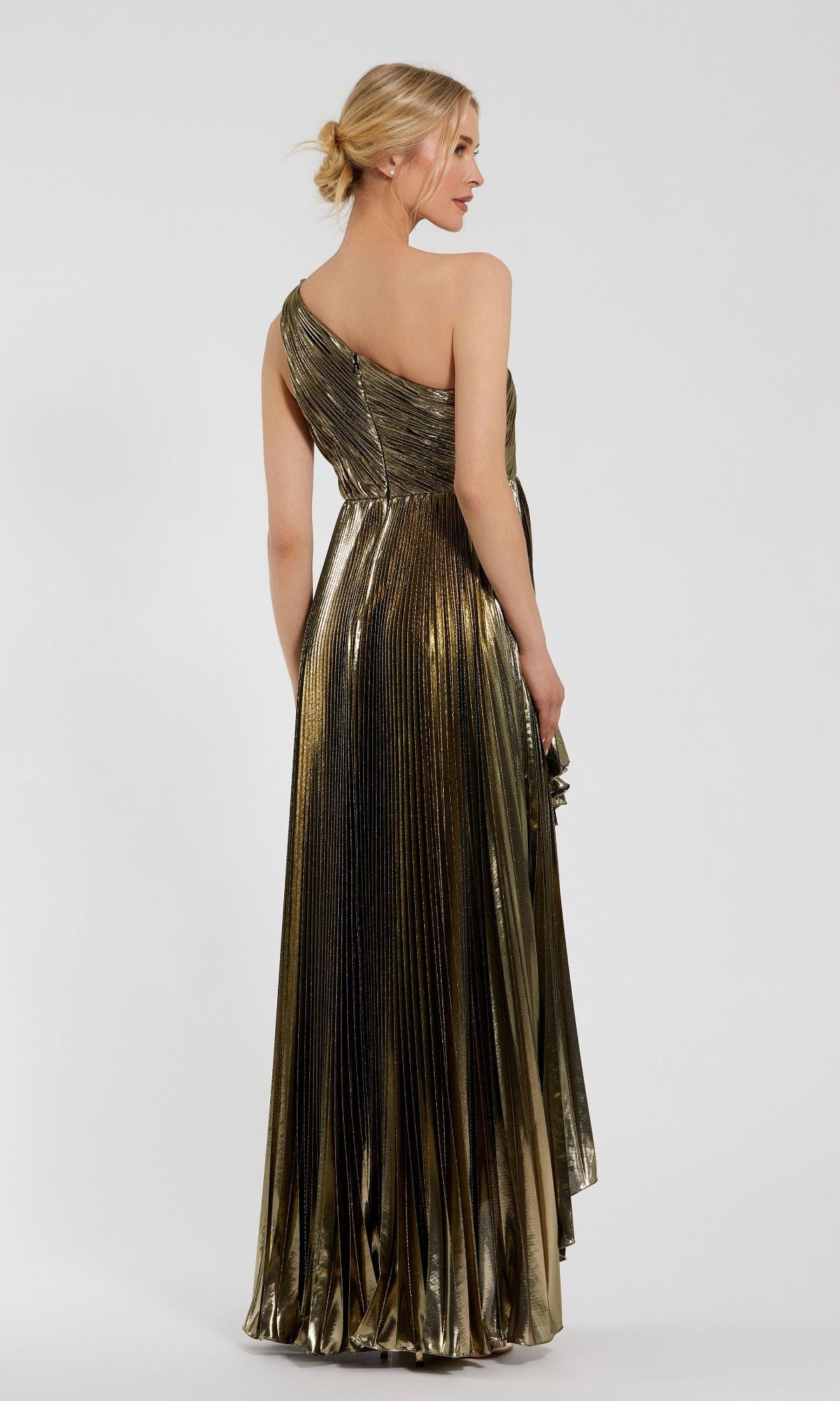 A woman faces away from the camera, modeling the Mac Duggal 49910 Gold Pleated Prom Dress. The long evening gown features a one-shoulder design and elegant pleats, set against a plain white background.